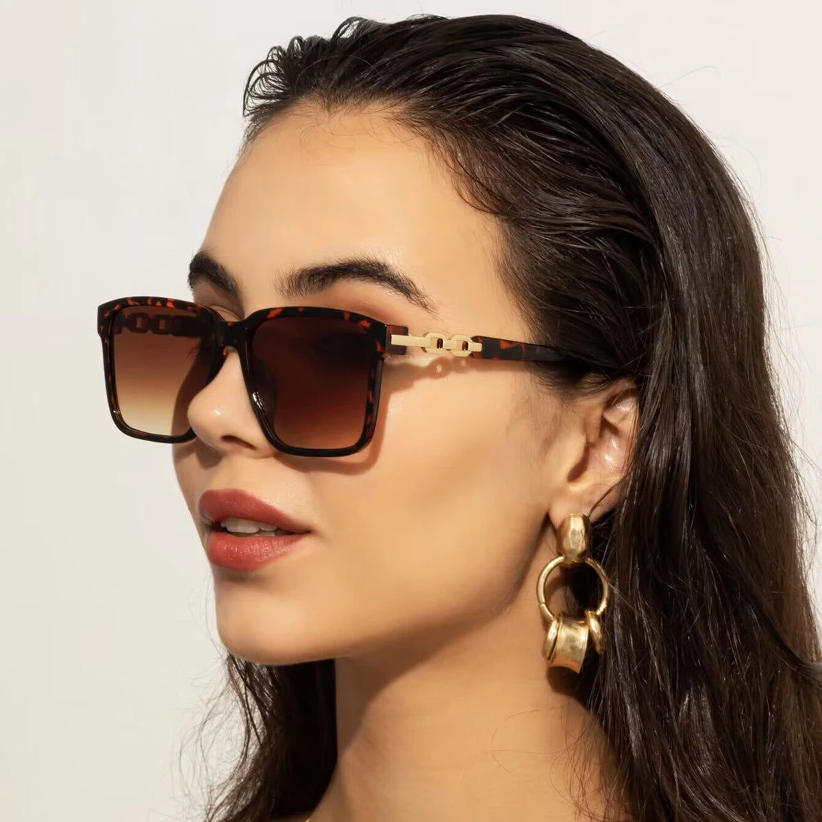 Lorya — Übergroße quadratische Sonnenbrille mit goldenen Kettenglied-Bügeln