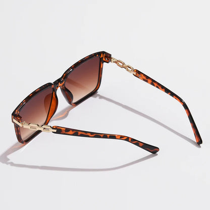 Lorya — Übergroße quadratische Sonnenbrille mit goldenen Kettenglied-Bügeln